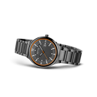 Watch shown in three-quarter profile with dark dial, gold-tone bezel, and metal bracelet.