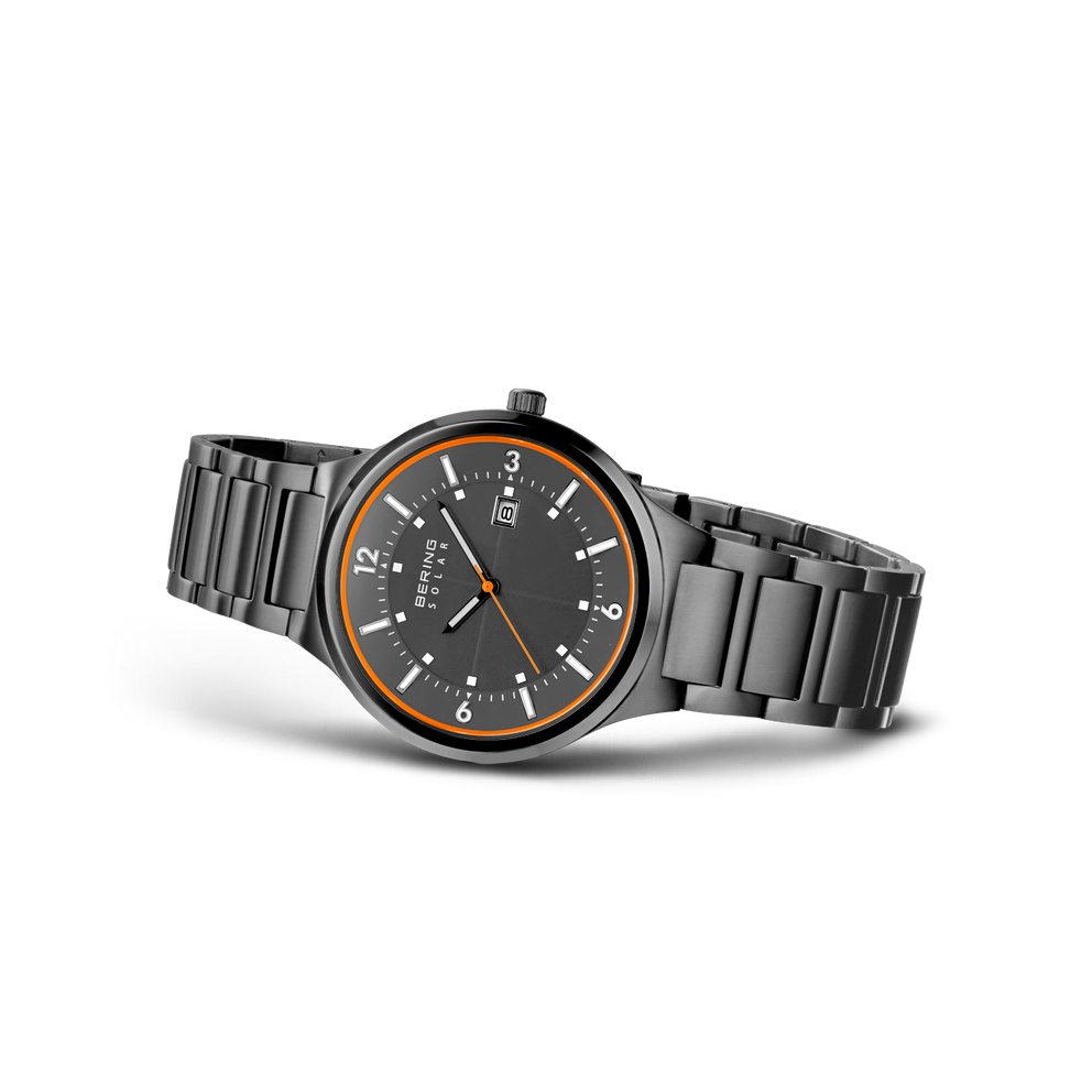 Watch shown in three-quarter profile with dark dial, gold-tone bezel, and metal bracelet.