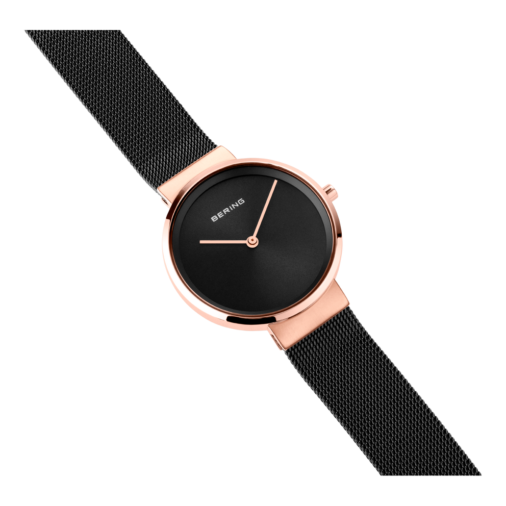 BERING wristwatch with round black dial, rose gold case, and black mesh band, shown at angled perspective.