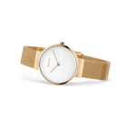 Reloj de pulsera redondo con esfera blanca y correa mesh dorada, fotografiado de lado
