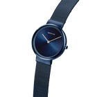 Reloj minimalista azul oscuro con correa de malla, vista lateral mostrando esfera y detalle de correa texturizada.