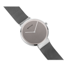 Reloj BERING en ángulo con correa de malla metálica enrollada alrededor de la caja y esfera gris visible