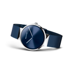Orologio ripreso lateralmente con bracciale maglia scura e quadrante blu navy.