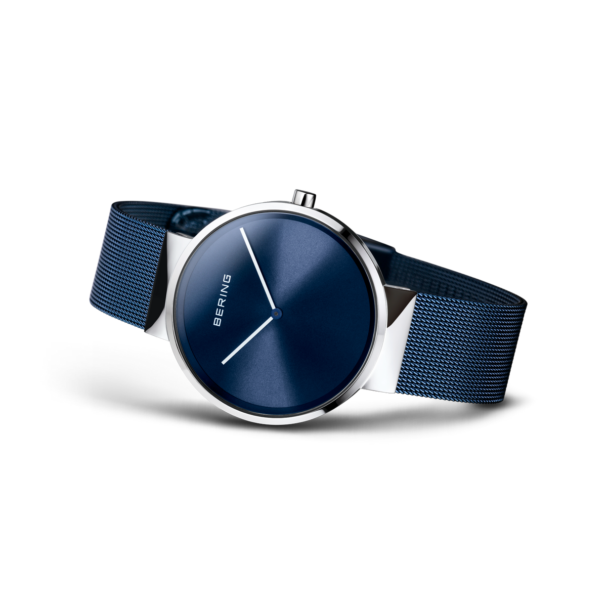 Orologio ripreso lateralmente con bracciale maglia scura e quadrante blu navy.