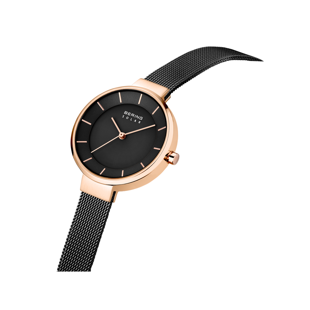 Orologio rotondo con cassa oro rosa e quadrante nero, indossato su cinturino mesh scuro, vista angolata