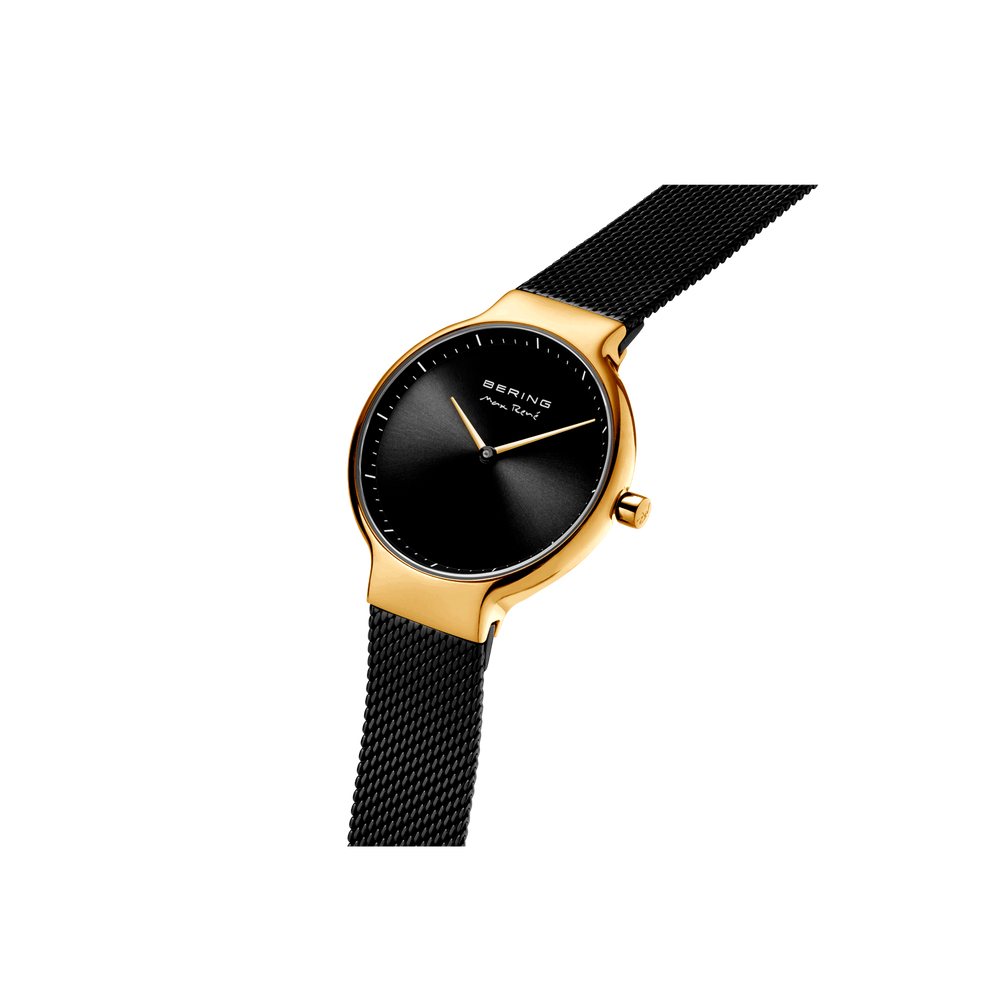 Gold-toned round watch with black dial and black mesh strap, angled view from above.