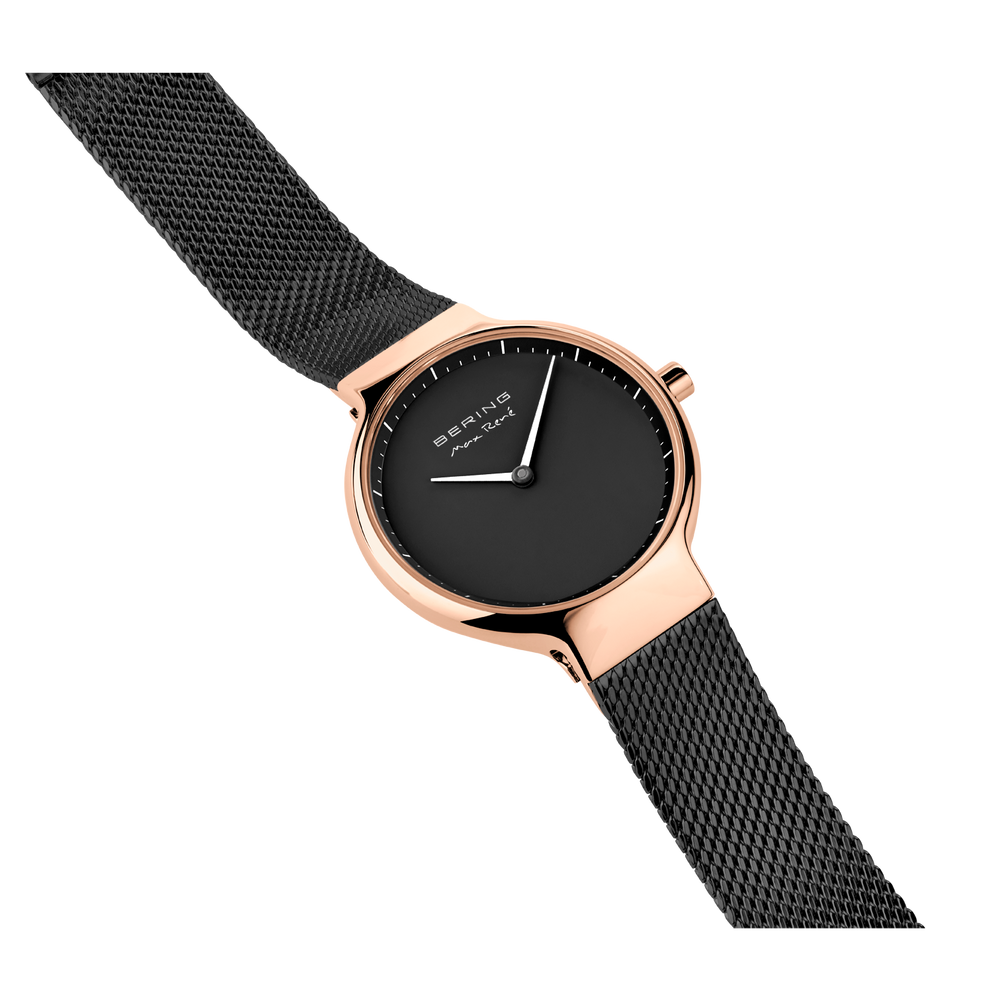 Rose gold round watch with black dial and minimalist hands, black mesh metal band angled across white background.