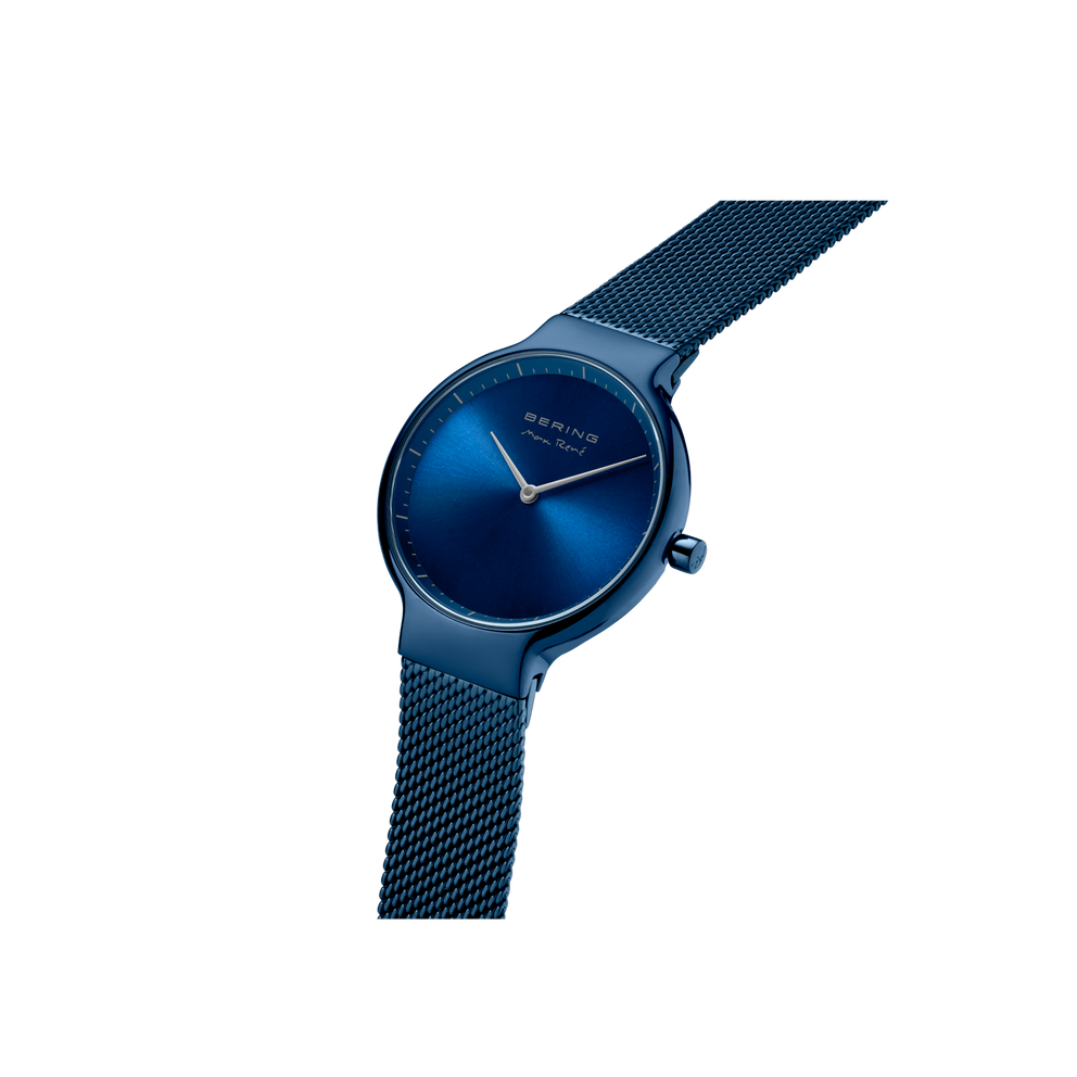 BERING horloge in schuine hoek: marineblauw wijzerplaat met witte wijzers en mesh-band.