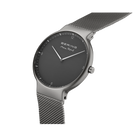 Orologio da polso con quadrante nero rotondo, cassa in acciaio e cinturino maglia metallica, vista laterale