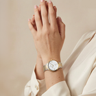 Orologio da polso con quadrante bianco e cinturino bicolore al polso.