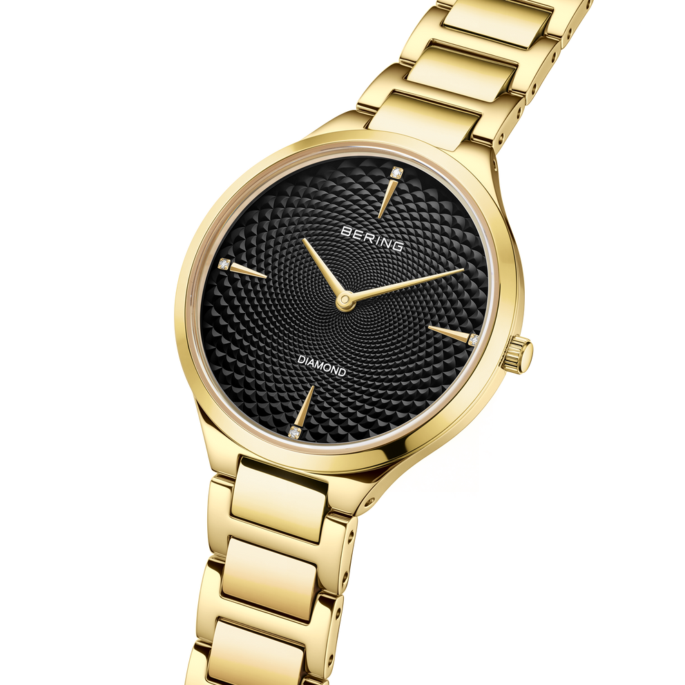 Orologio BERING con cassa dorata e bracciale a maglie, quadrante nero strutturato visto dal profilo
