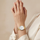 Orologio da polso dorato con braccialetto a maglie, quadrante bianco e indici minimalisti, indossato