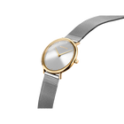 BERING horloge met goudkleurige kast, zilveren wijzerplaat en stalen mesh-band, gefotografeerd onder hoek.