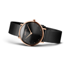 Watch with rose gold case, black dial, and black mesh band, shown at three-quarter angle