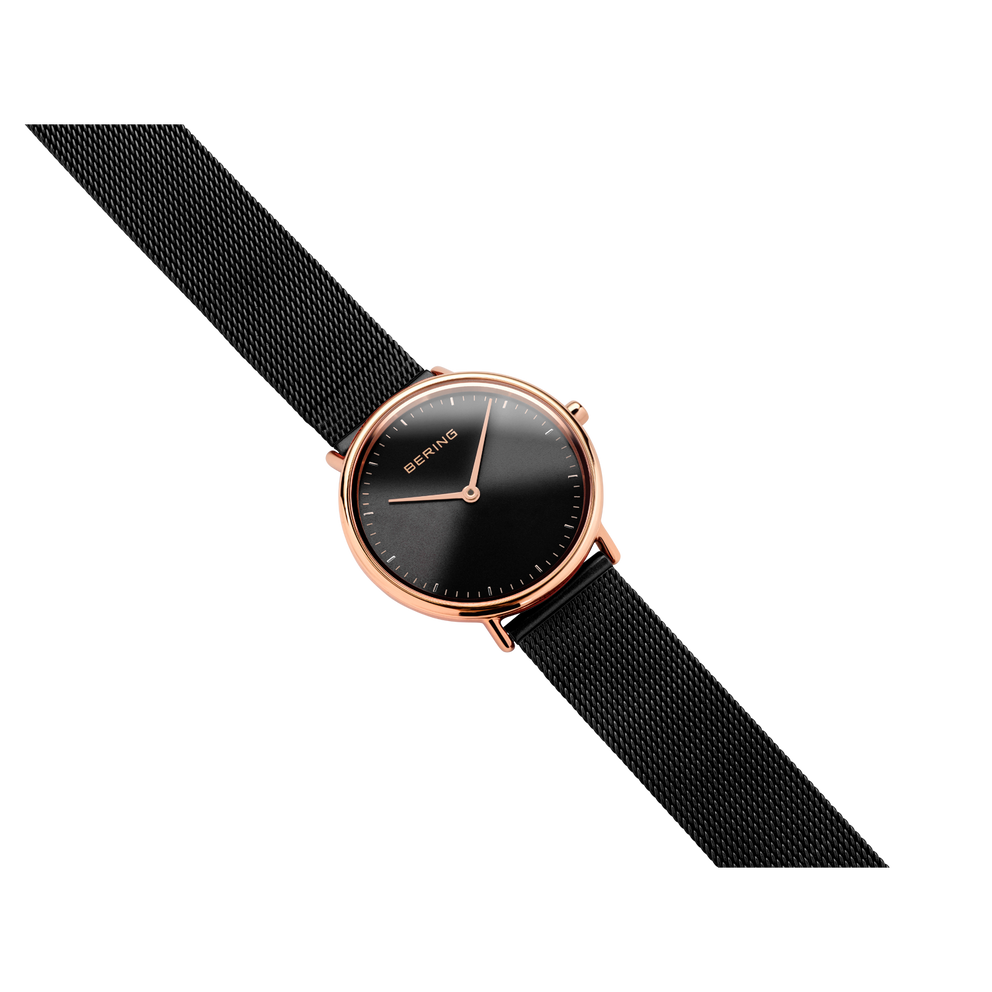 Rose gold watch with black dial and fabric strap, displayed at a diagonal angle
