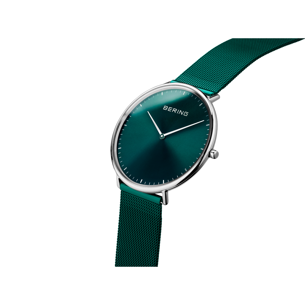 Wristwatch with teal dial, metal case, and mesh band shown at angle highlighting case and strap