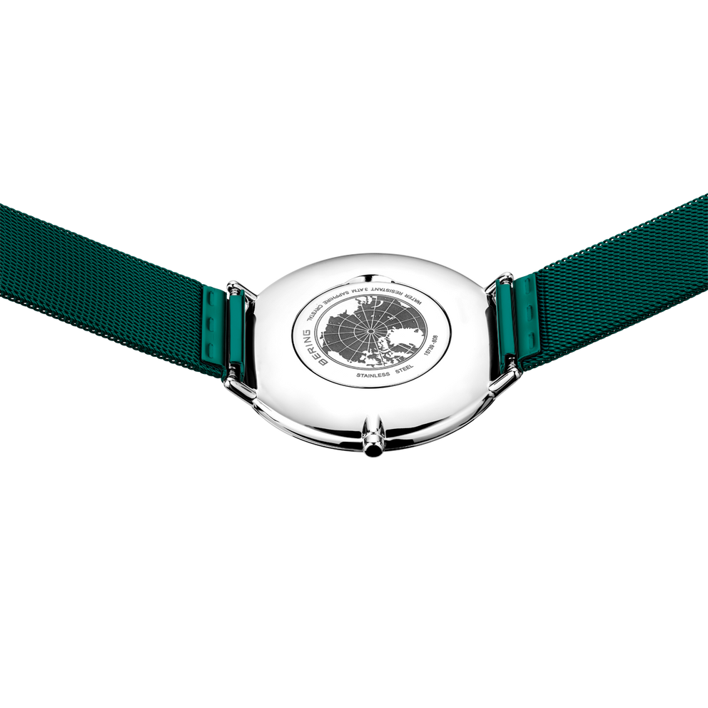 Round silver watch with dark green fabric strap, shown from above with engraved circular dial detail visible.