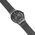 Montre-bracelet BERING avec cadran foncé, design minimaliste et bracelet maille gris en vue diagonale
