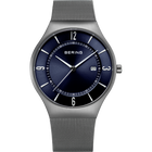 Reloj con pulsera de malla plateada, esfera azul marino, manecillas blancas e índices horarios, ventana de fecha