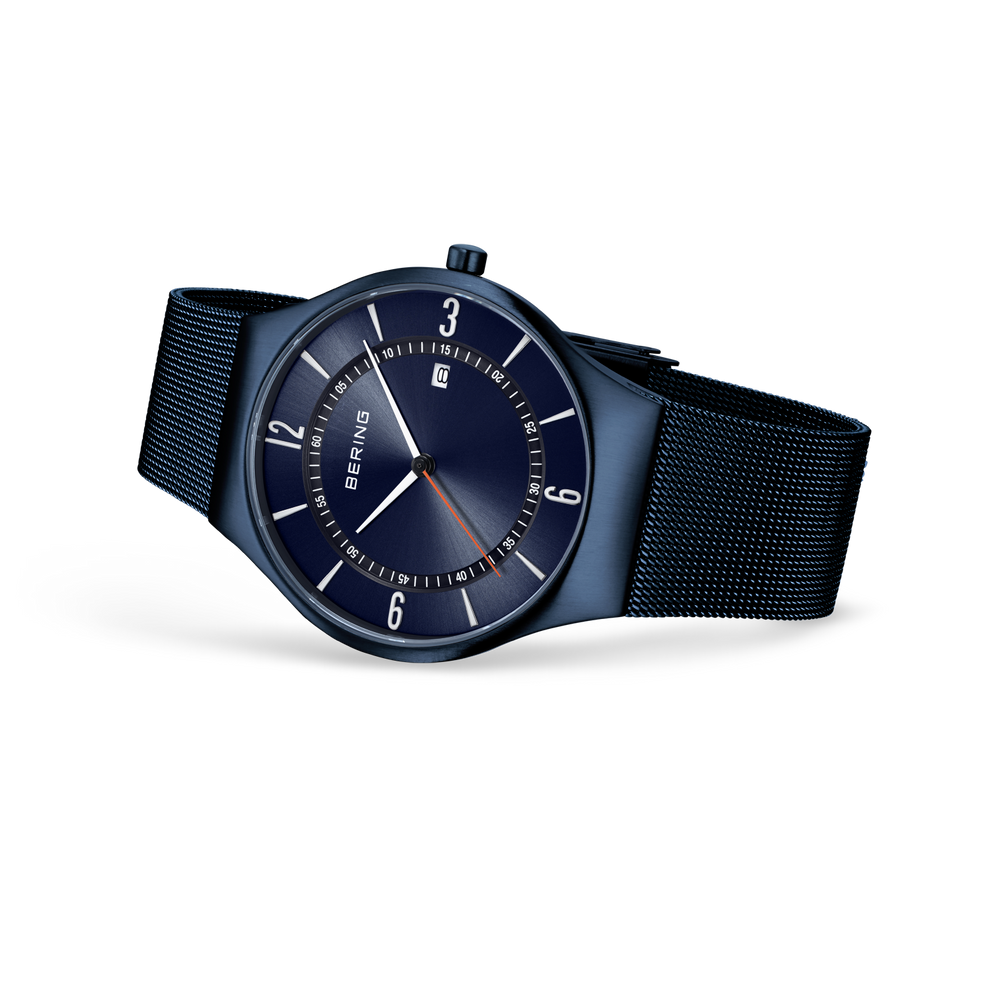 BERING wristwatch with dark blue dial and black mesh band, angled three-quarter view of case and strap.