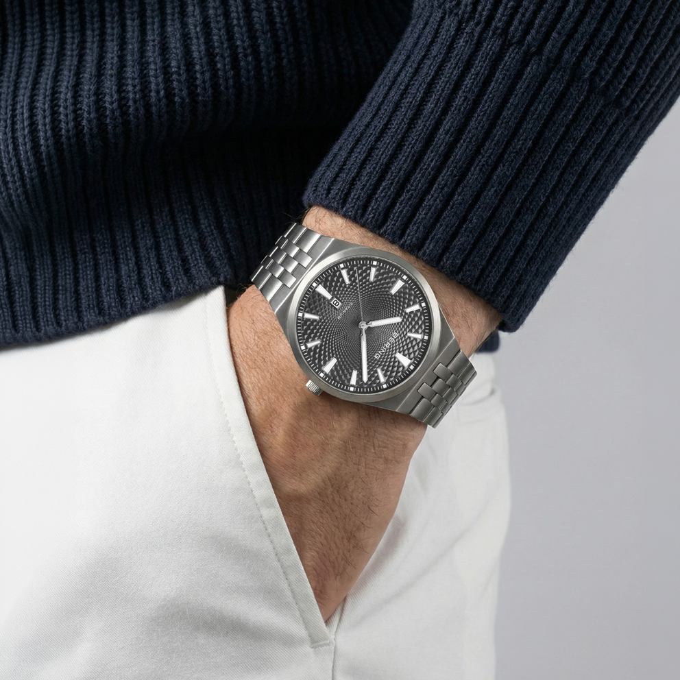 Reloj BERING llevado en la muñeca con suéter azul marino y pantalones blancos
