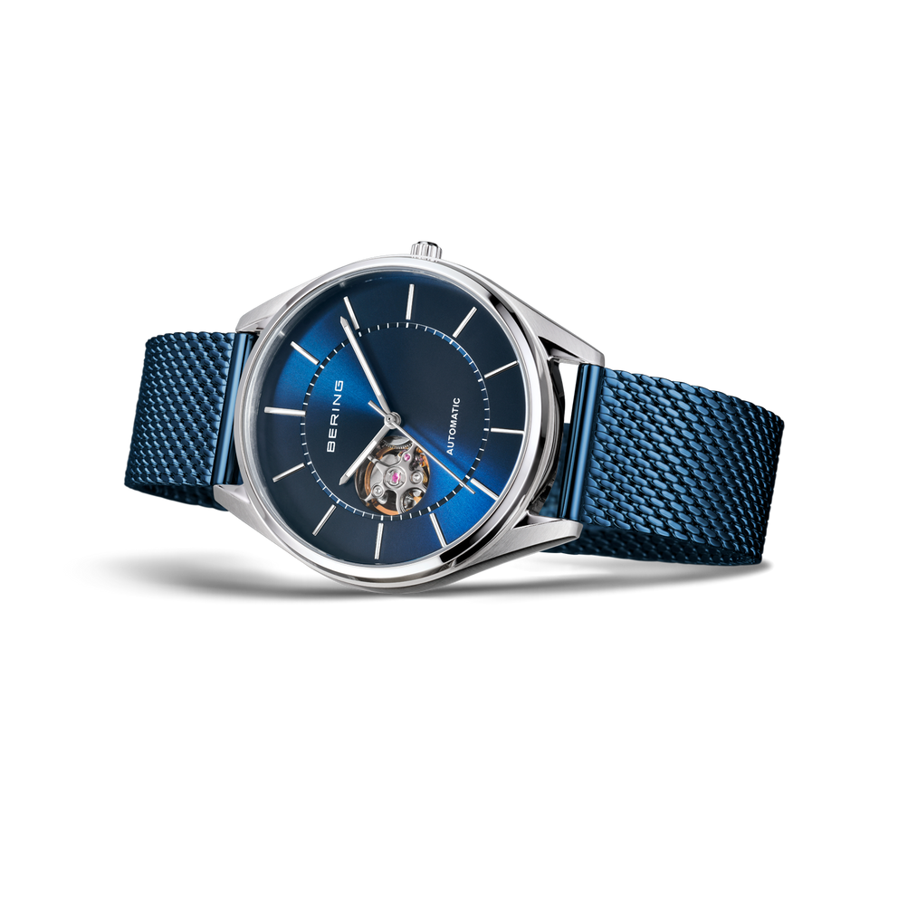 Watch with silver case, dark blue dial with white markers, and blue textile strap, side view showing transparent center