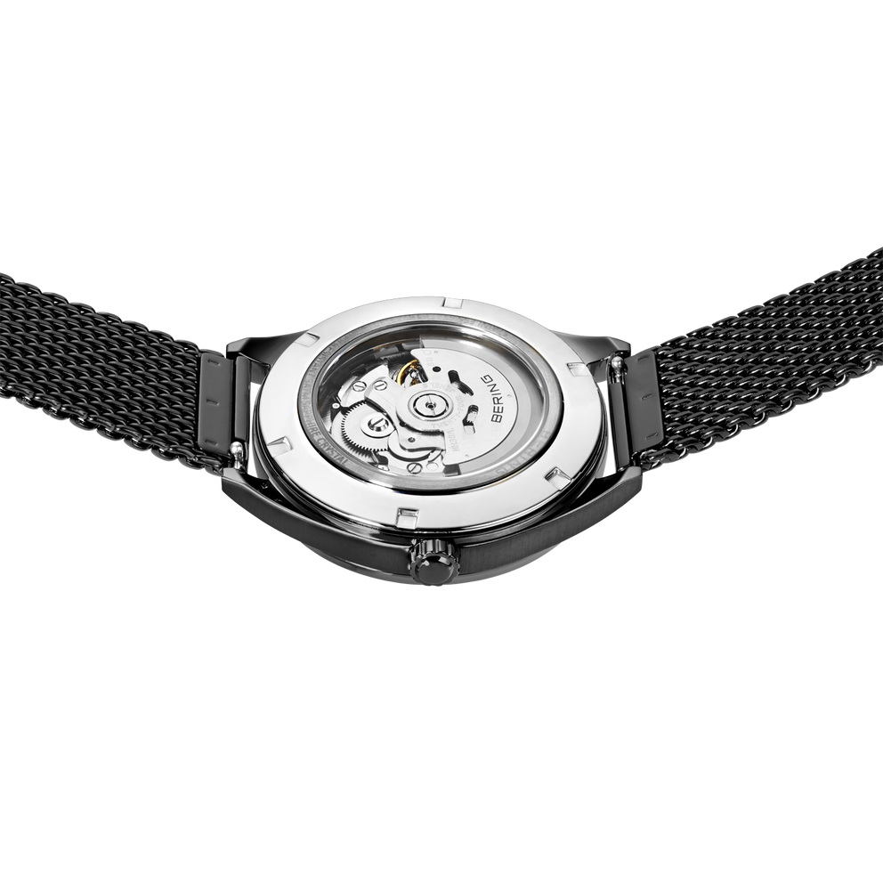 Watch back with transparent case revealing the visible movement, black mesh band