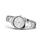 Sølvfarvet metalarmbandsur med rund urskive og sort bezel, set fra siden.