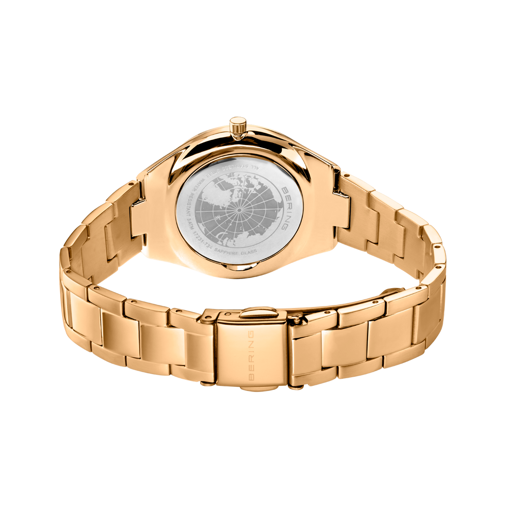 Ur set bagfra med roséguldmetalarmband og gravert baglåg.