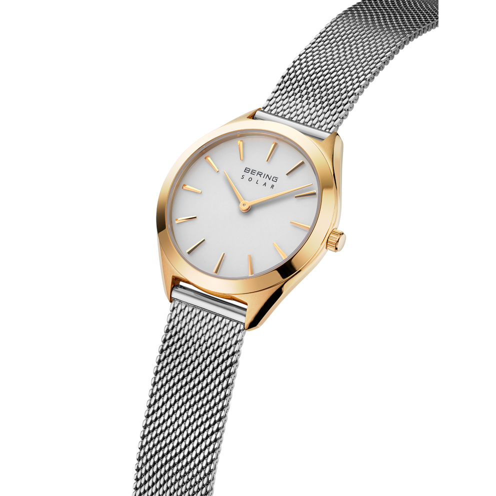 Orologio BERING con cassa color oro rosa e quadrante bianco, visto di lato con cinturino maglia