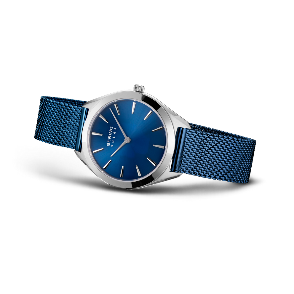 Orologio color argento con quadrante blu e cinturino in maglia metallica blu, vista a tre quarti.