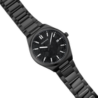 Reloj de pulsera negro con pulsera de eslabones metálicos, fotografiado en ángulo mostrando la esfera con marcadores blancos