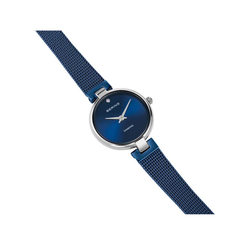 Montre BERING : boîtier rond argenté, cadran bleu foncé, bracelet maille bleu marine, vue de détail.