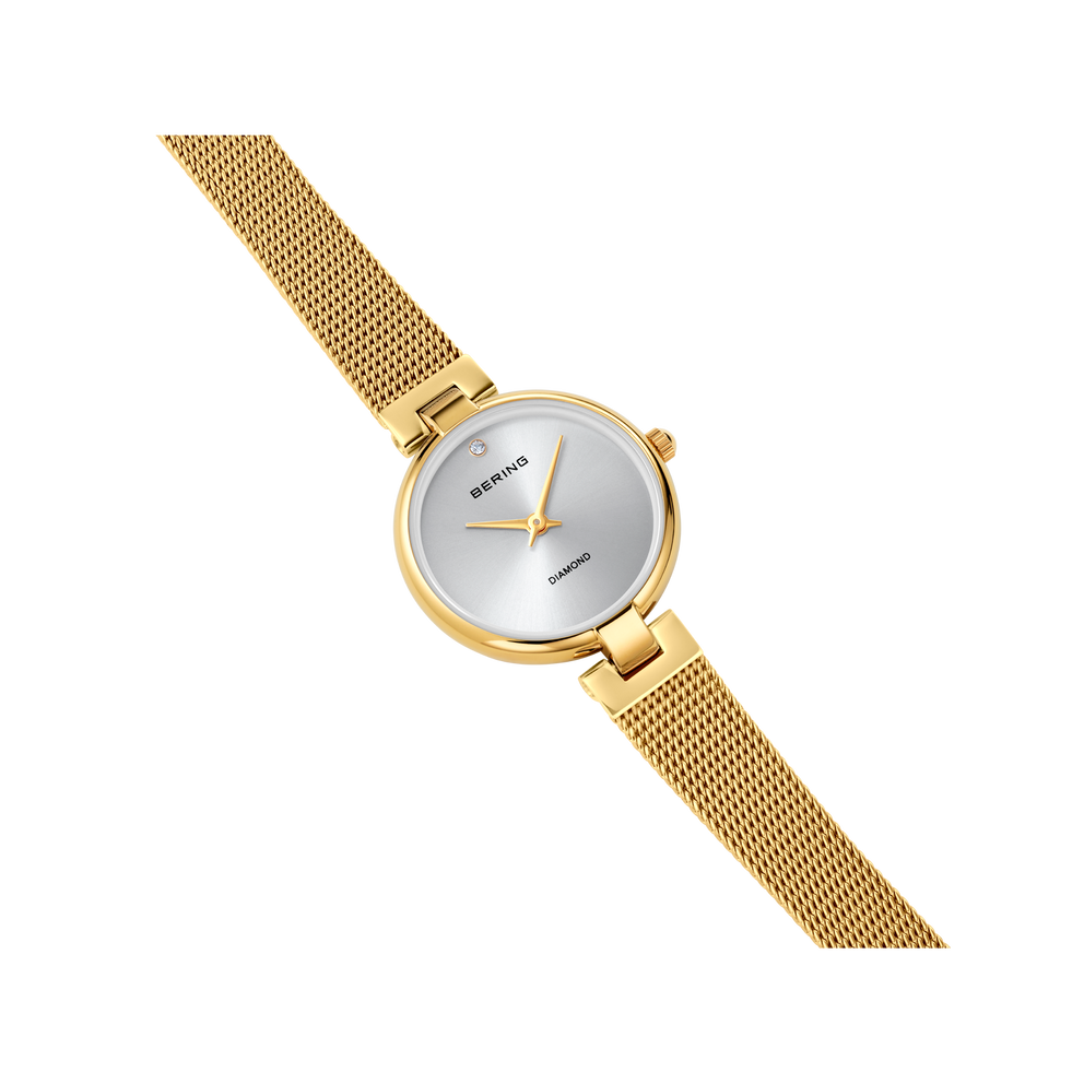 Orologio da polso BERING con cassa rotonda dorata e cinturino mesh champagne, mostrato ad angolo su sfondo bianco.