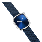 Angled view of square watch case with metallic finish, dark blue textured strap, and blue dial with white hands at 3 o'clock.