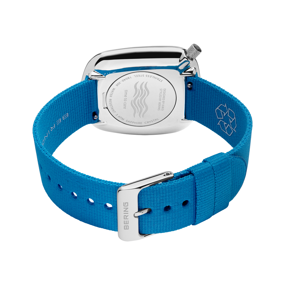 Square silver watch case with blue fabric strap and adjustment holes, viewed from above.
