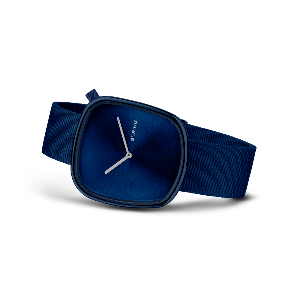 Montre carrée bleue avec aiguilles blanches et bracelet en tissu bleu foncé, vue de côté