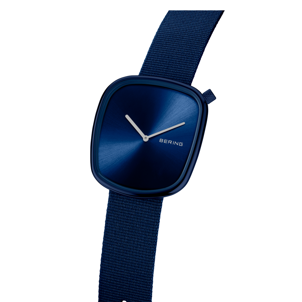 Montre BERING à cadran bleu foncé arrondi et aiguilles blanches, vue en angle avec bracelet en tissu bleu
