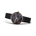 Reloj en vista lateral con correa de malla oscura, esfera azul oscuro con números romanos y manecillas doradas.