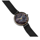 Reloj redondo con esfera oscura marmorizada, caja y agujas doradas, pulsera malla negra, vista angular.