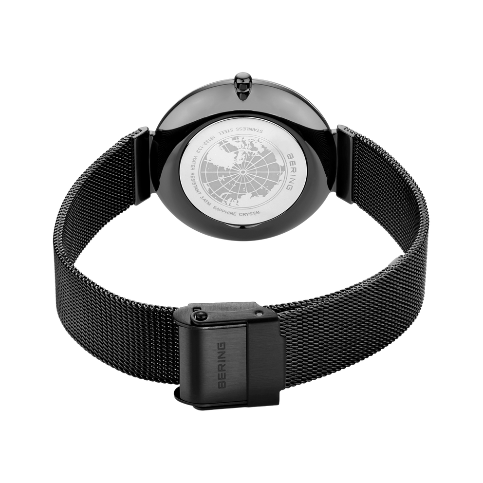 Tapa trasera con cristal transparente mostrando el mecanismo, pulsera malla negra y emblema calavera.