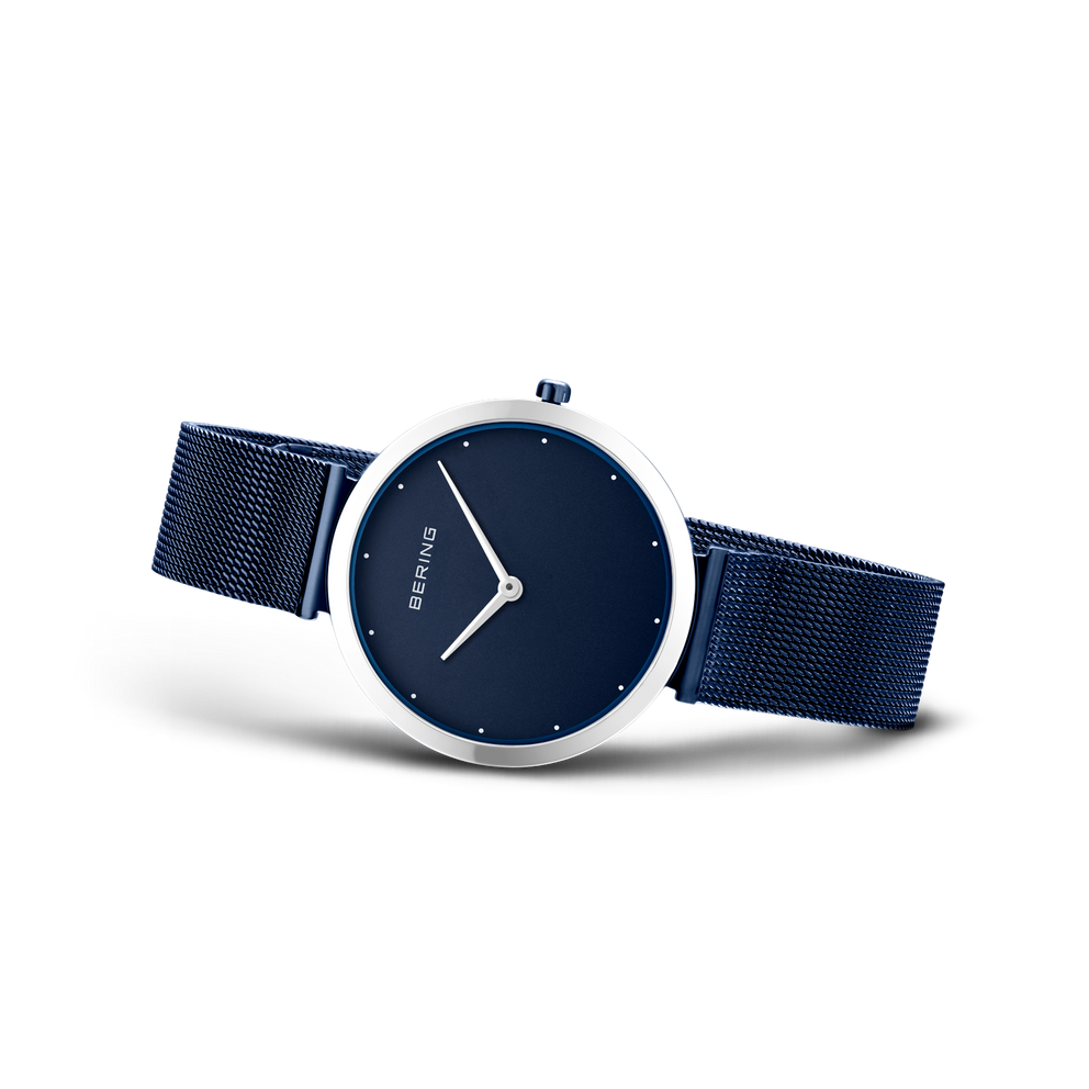 Horloge met donkerblauwe wijzerplaat, witte uurmarkeringen en wijzers, zilveren kast, donkerblauwe mesh-band