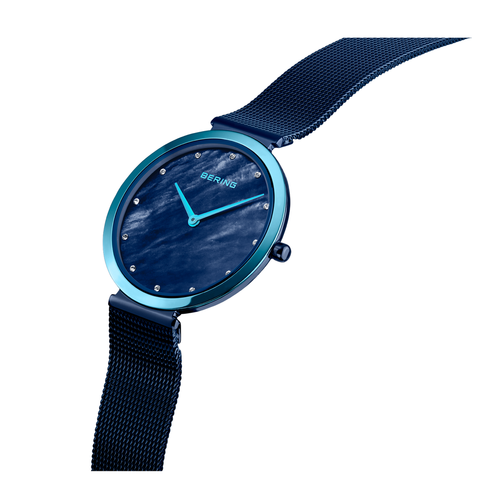 BERING wristwatch with dark blue dial, teal case rim, and navy mesh strap, angled detail view.