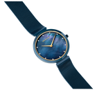 Reloj con esfera azul oscuro, índices y manecillas doradas, correa azul oscuro, vista angular sobre fondo blanco.