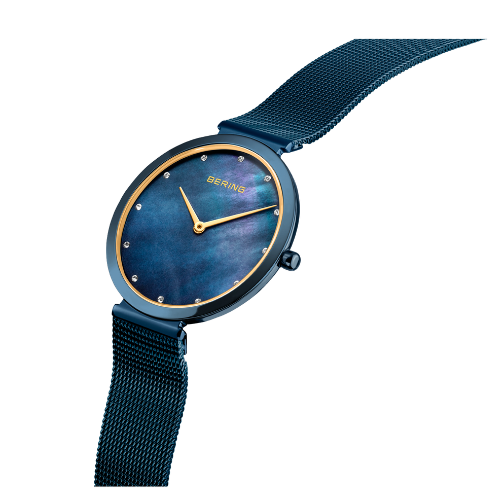 Reloj BERING 18132-399 visto desde el lado, esfera azul con índices y agujas dorados, pulsera malla
