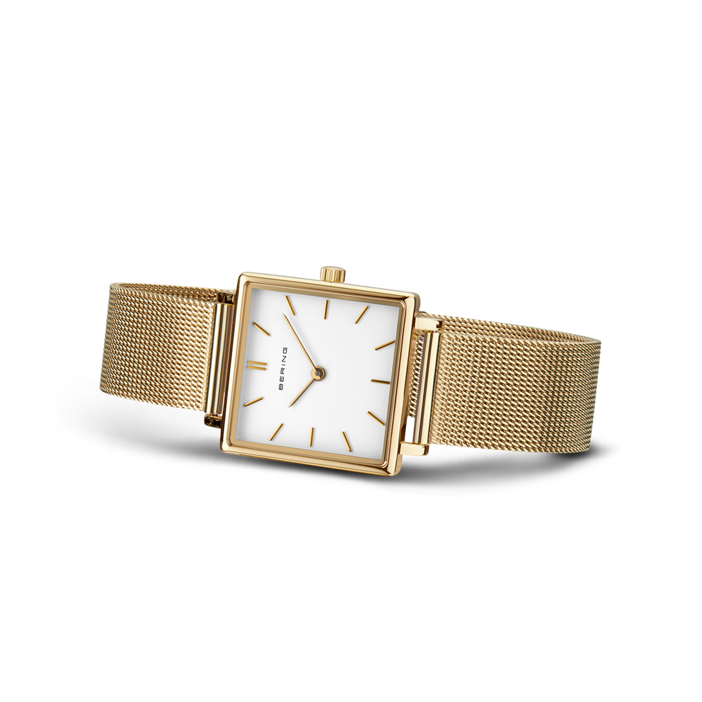 Square gold-tone watch with white dial and mesh bracelet, angled view of case and band