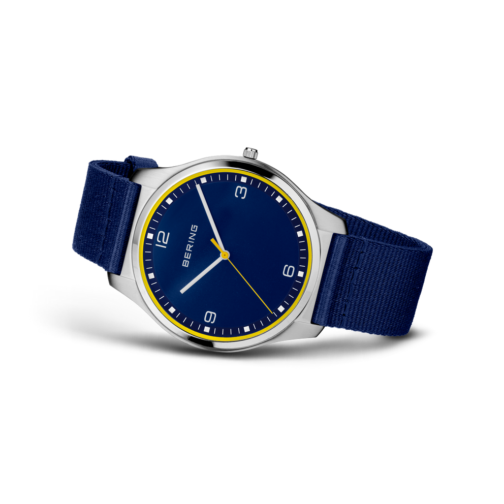 Wristwatch with dark blue dial, gold bezel, and dark blue textile strap, shown at three-quarter angle.
