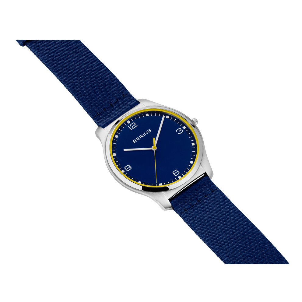 Round silver watch with dark blue dial, gold trim, and navy fabric strap.