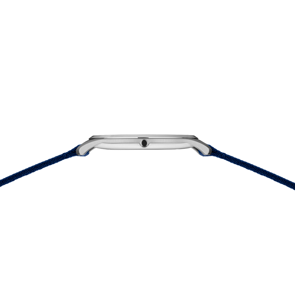 Square silver watch case with dark blue fabric strap, photographed from above