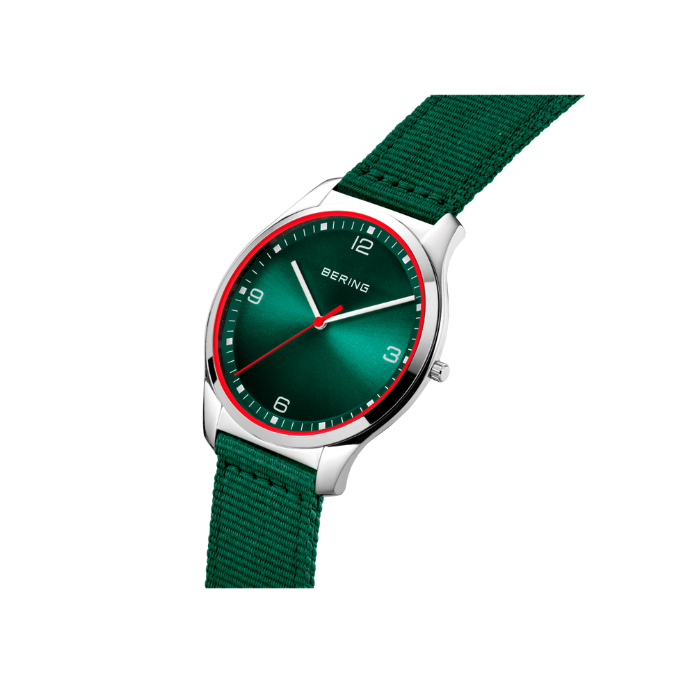Watch with dark green dial and bezel, silver case, and green fabric strap, photographed at angle